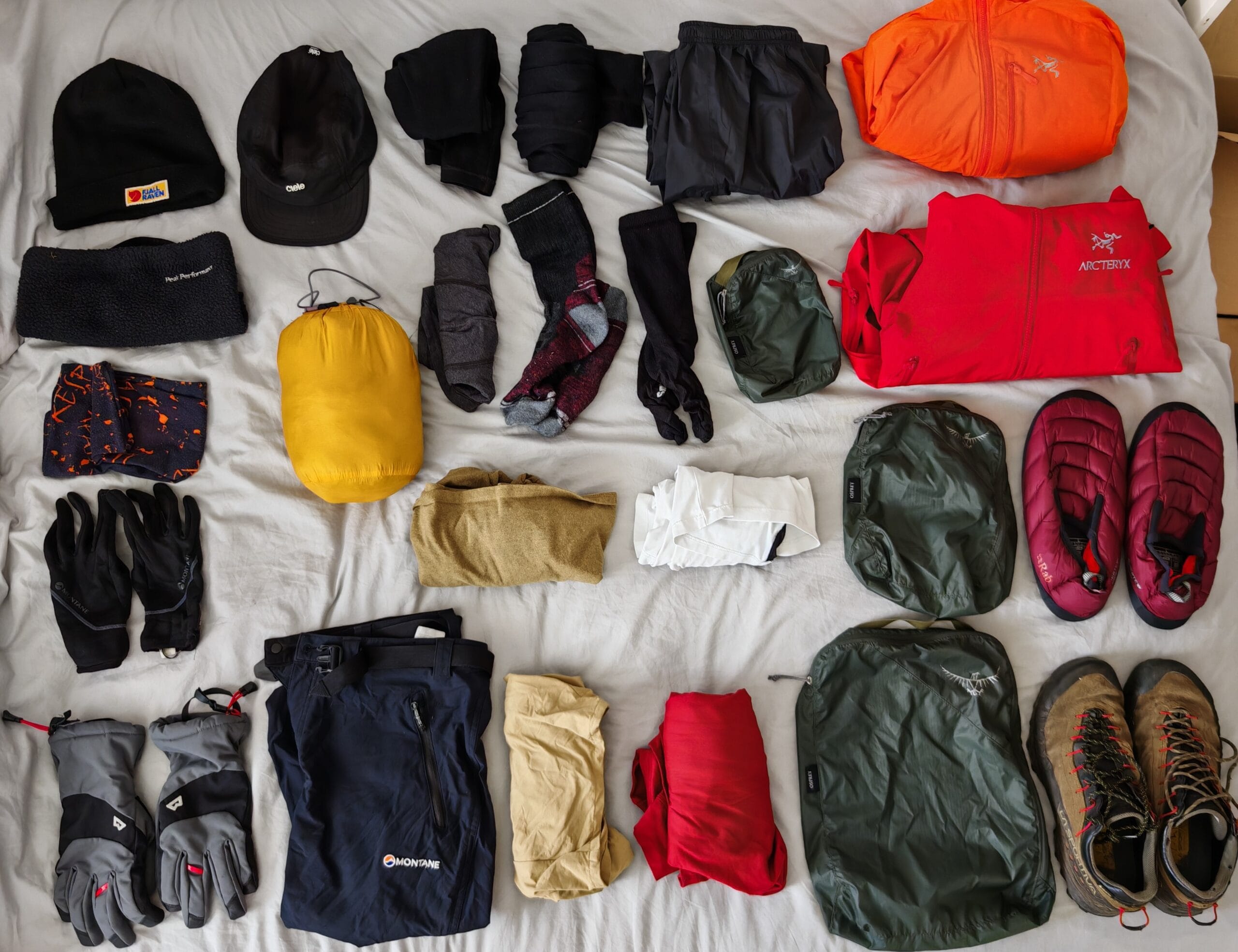 Technical mountain layering system showing a merino wool base layer, Arc'teryx Proton LT mid-layer, and Gore-Tex hard shell.