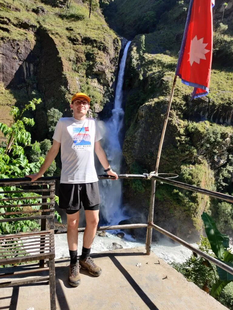trekker standing in front of a waterfall on Day 1 trekking the Annapurna Circuit Himalayas Trail