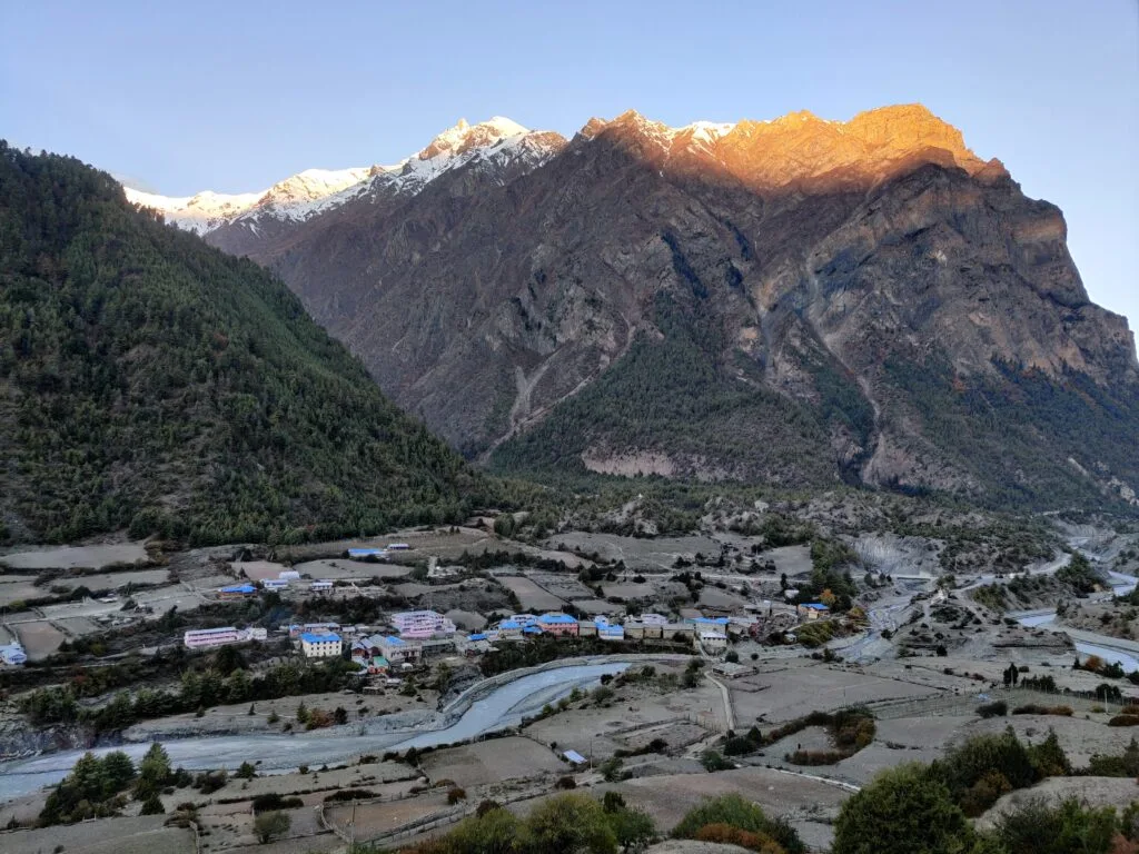 Sunset mountain view near upper Pisang with lower Pisang in shade under Annapurna Massif