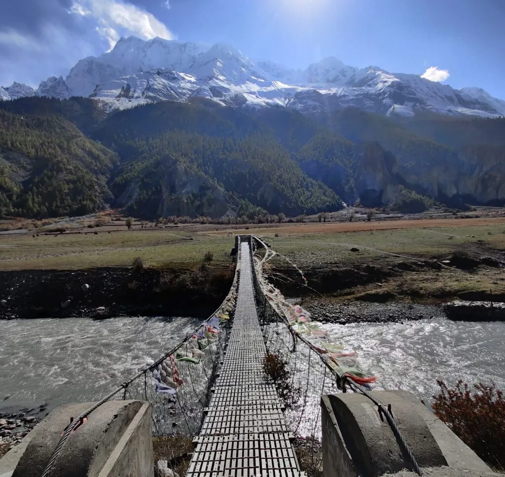 A tibetan style suspension bridge with vast Annapurna Massif behind