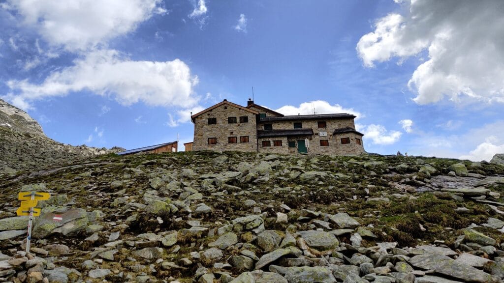 The Frisenberghaus mountain hut standing ontop of a rocky outcrop in the Austrian Alps