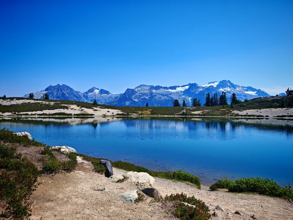 Elfin Lakes reflecting distant mountains with a bright blue sky