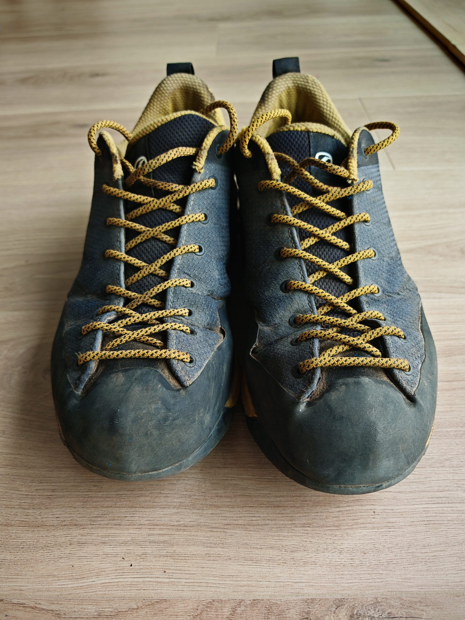 The Scarpa Mescalito Planet approach shoe resting on rocky terrain, highlighting the Vibram climbing zone toe.