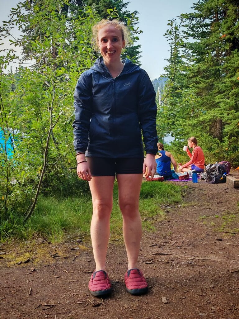Female camper wearing the Rab Cirrus Hut Slippers on dirt ground
