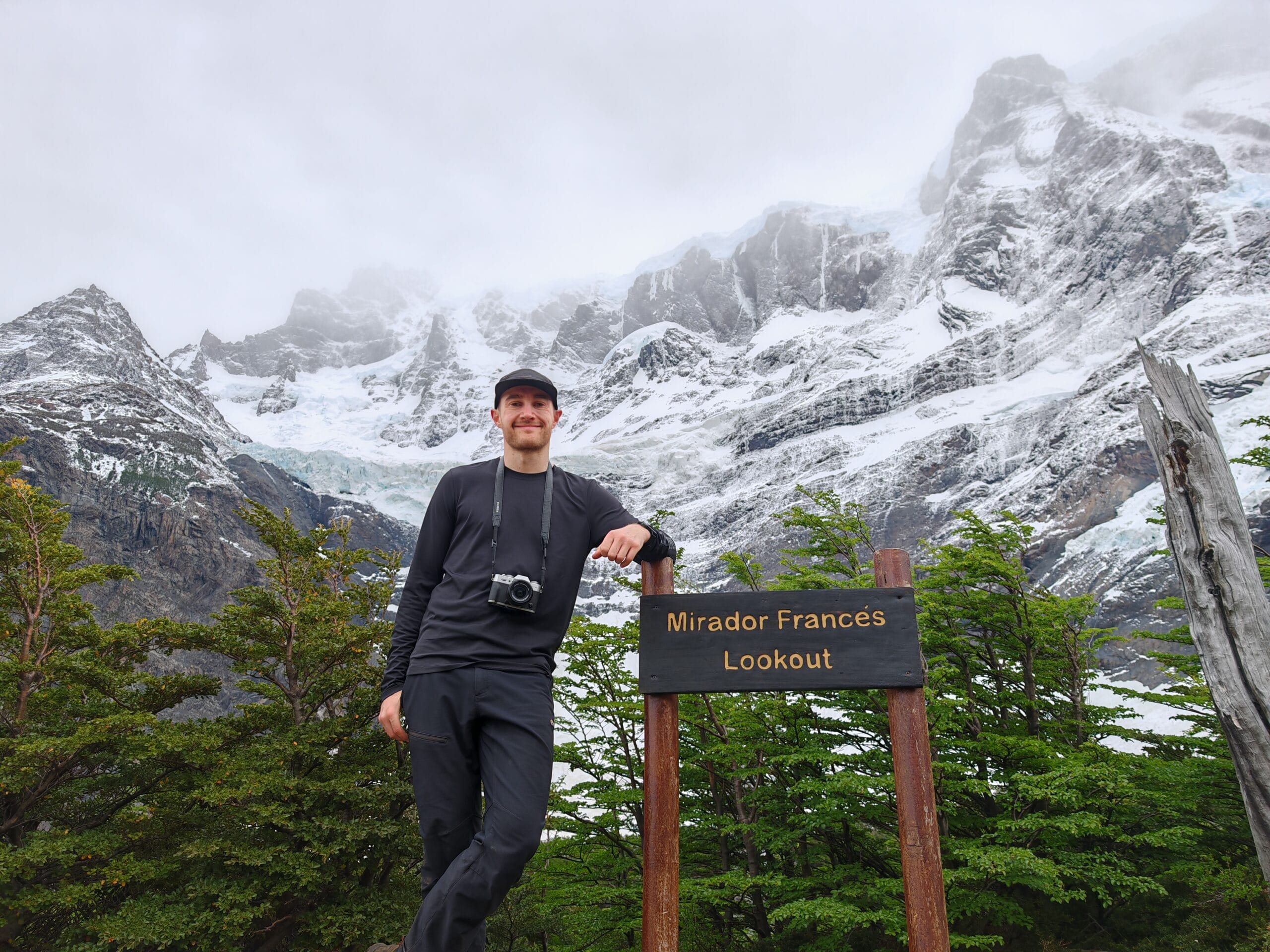 Mirador Frances with a male trekker leaning on the sign post in from of a wall of ice and rock in Torres del Paine National Park