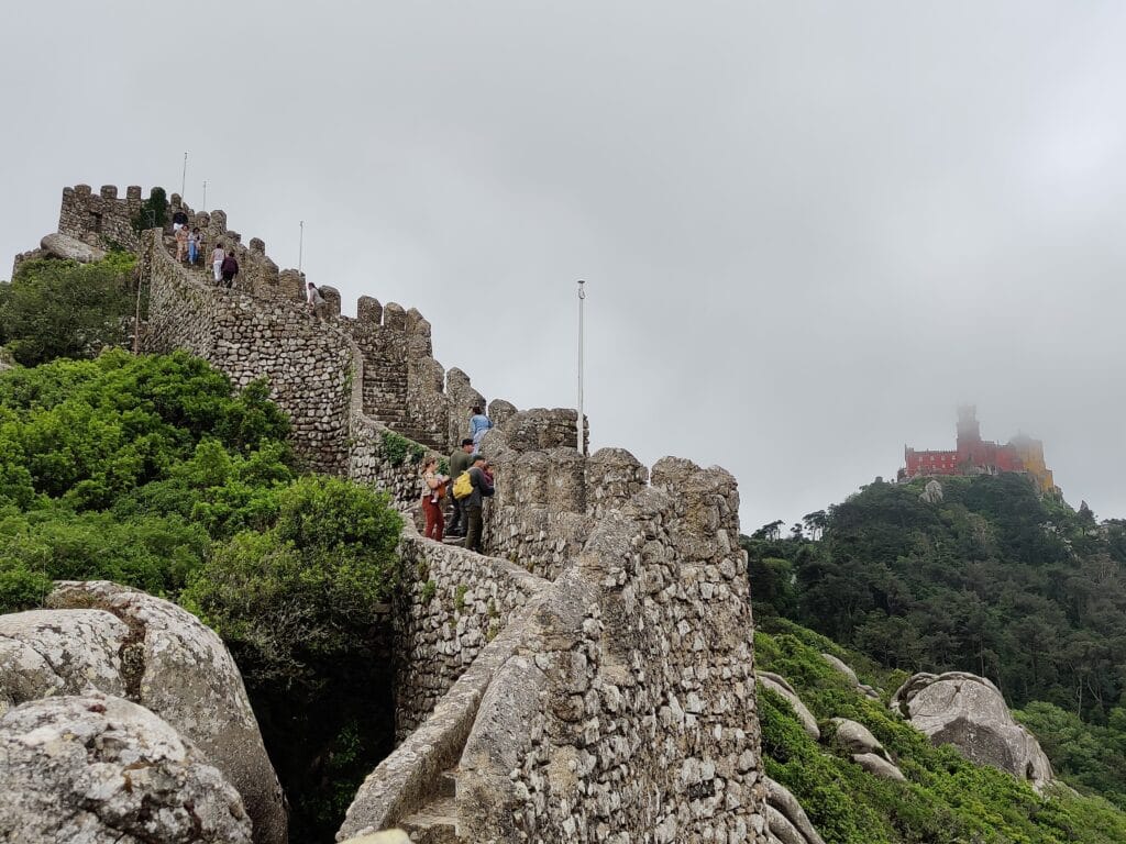 The Moorish castle with the National palace of Pena in clouds above as part of a Sintra Day Trip