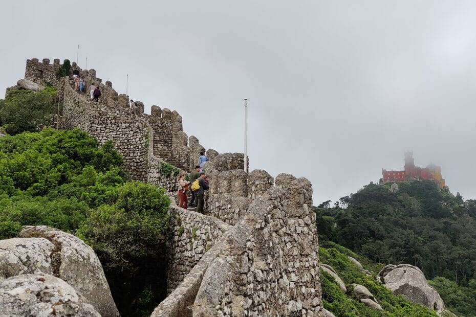 The Moorish castle with the National palace of Pena in clouds above as part of a Sintra Day Trip