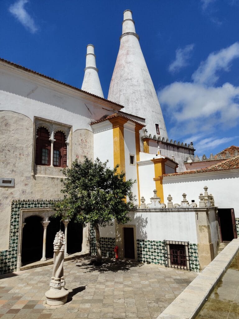 The National palace of Sintra with the iconic double chimneys with a sunny courtyard
