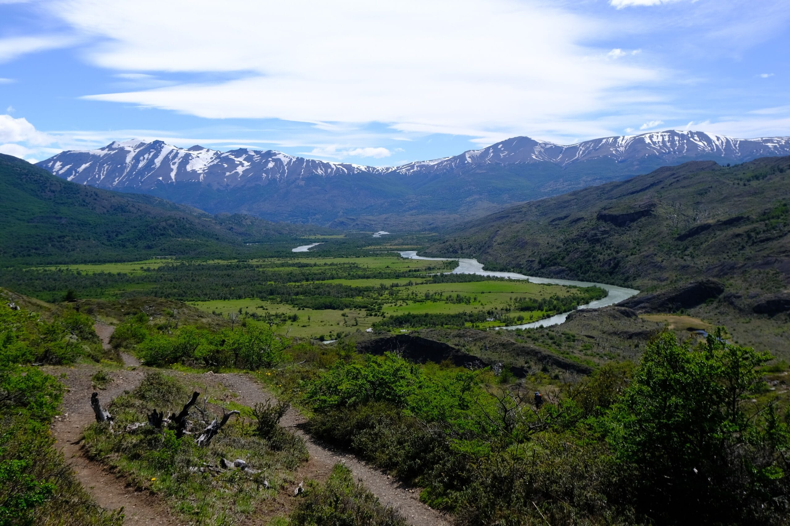 A view on the Patagonia O Circuit in the Torres del Paine National Park on the way to Seron Camp showing a winding river, fields and mountains in the background