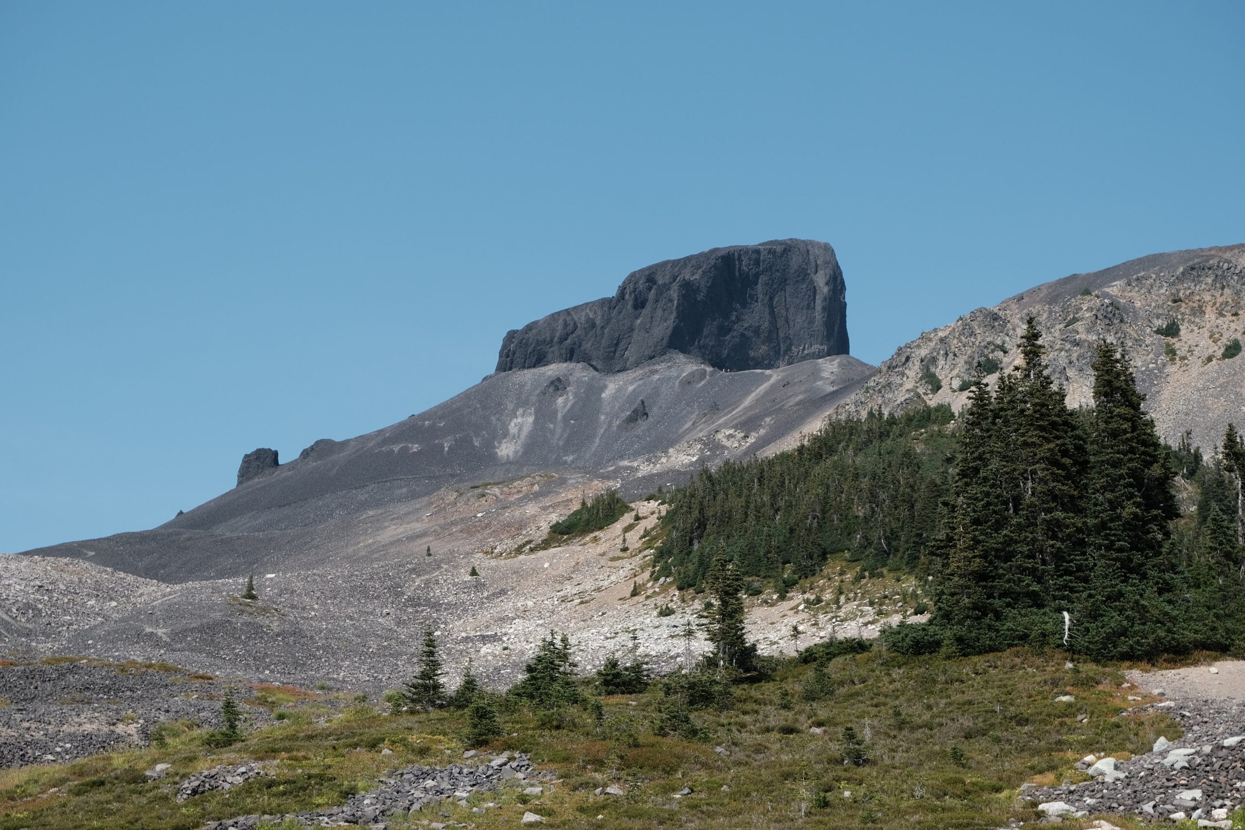 Black tusk above a scree slope with blue skies 