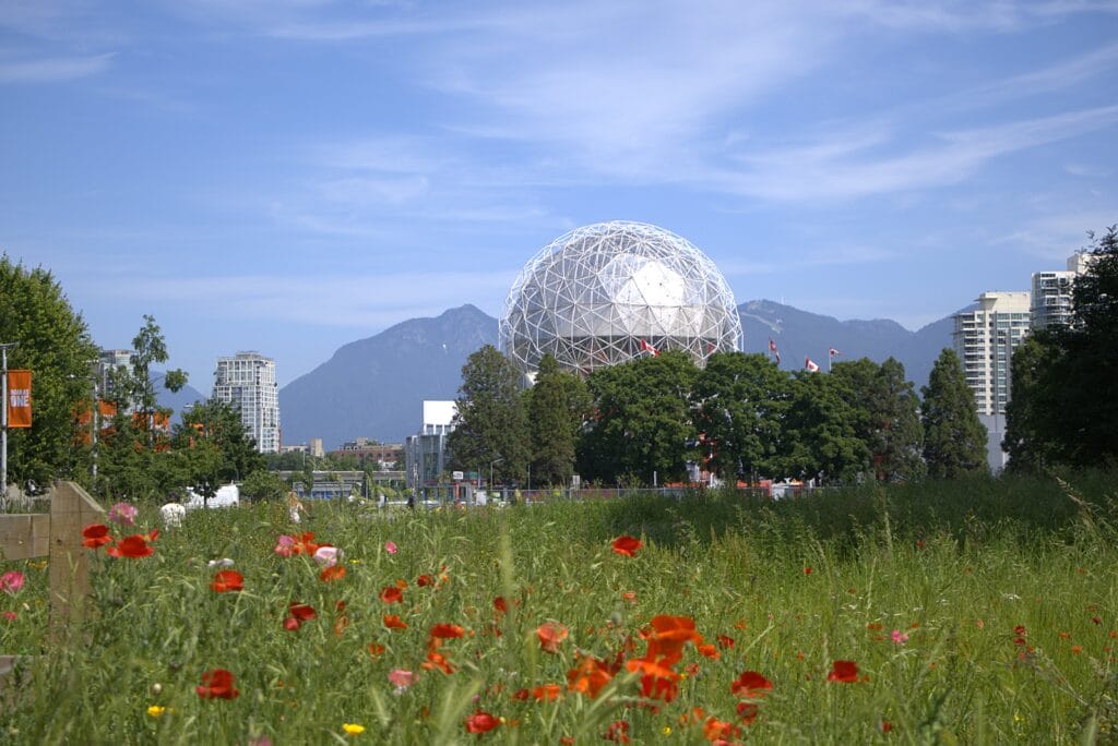 Science World with the recognizable metal dome with mountains behind and a meadow in the foreground, captured on a Fujifilm X-T30