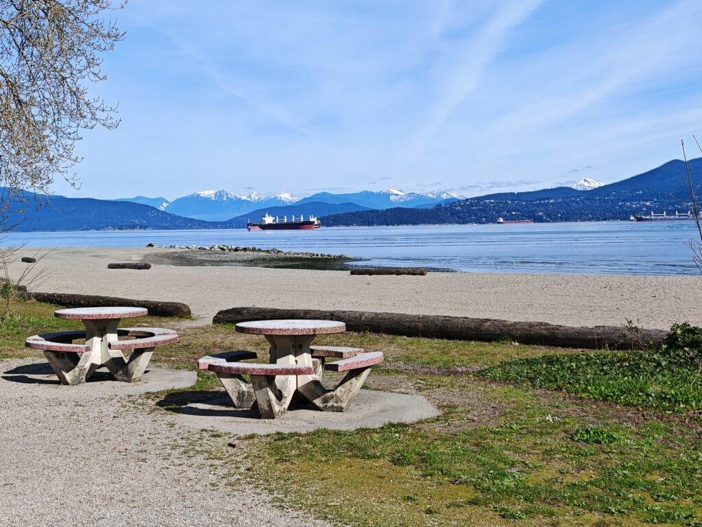 Spanish Beach with picnic tables, sand with cool water and mountain views in the background in Vancouver