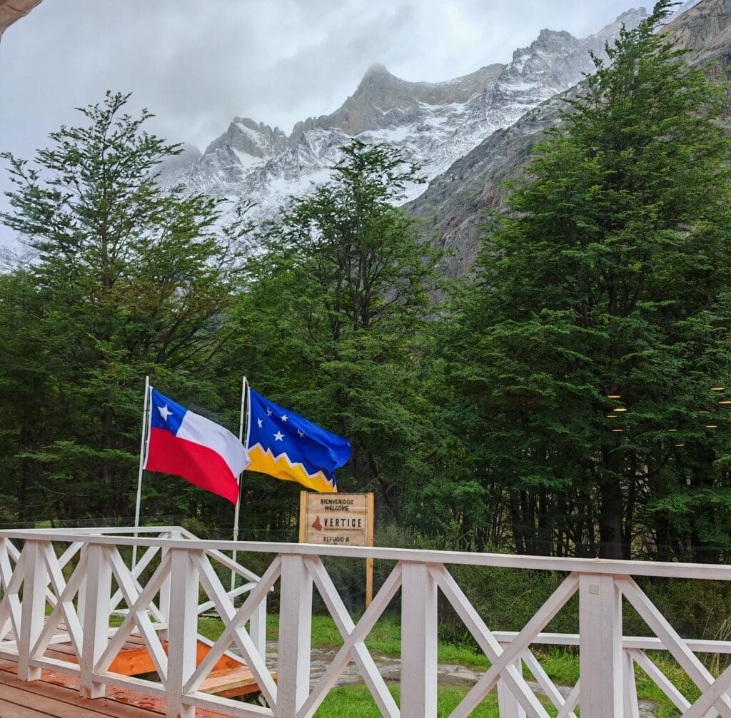 The terrace with white painted fence and flags flying at Grey Camp and mountains high above