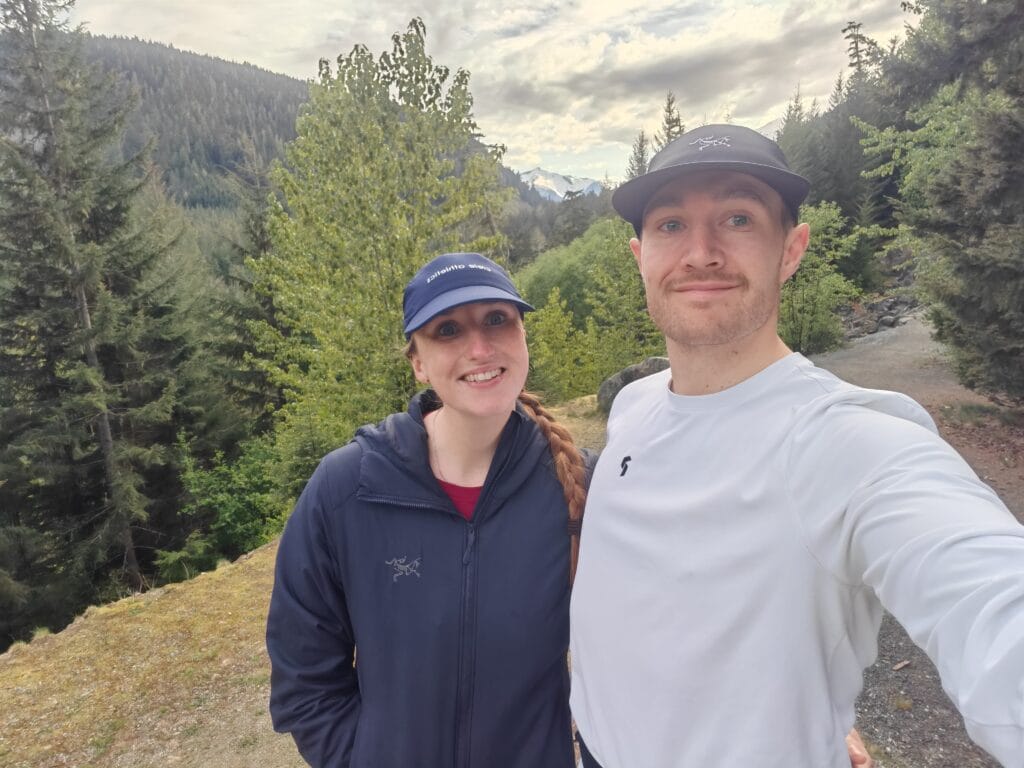 A trail running couple with the woman wearing the Arc'teryx Atom hoody for warmth at the trailhead in BC, Canada