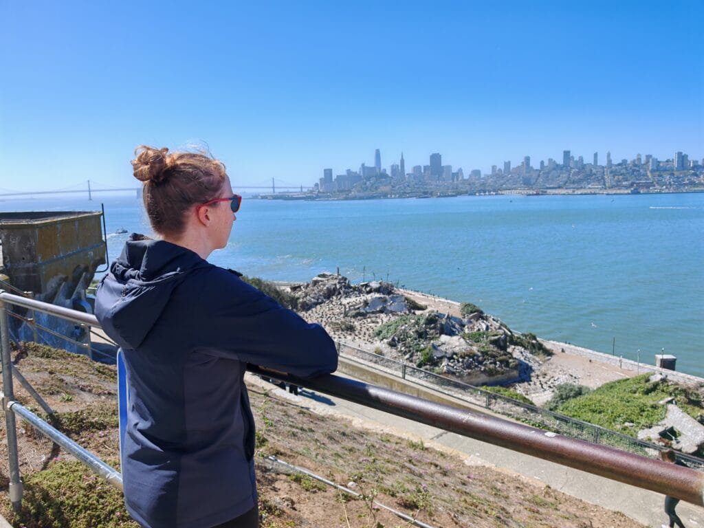 A rear view of the Arc'teryx Atom Jacket as a woman looks out over San Franisco