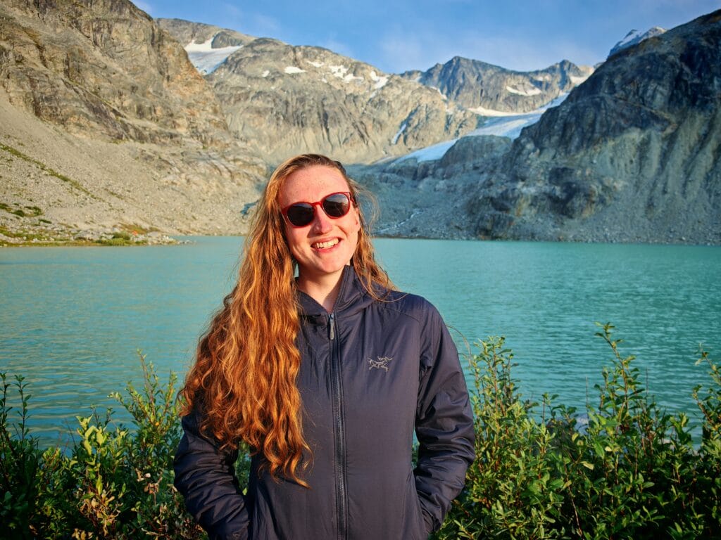 A female camper wearing the blue Women's Arc'teryx Atom Hoody at Wedgemount Lake in BC