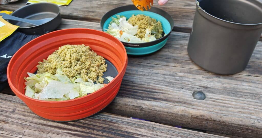 Camping bowls with couscous for dinenr showign the titanium mugs as part of camp cooking equipment