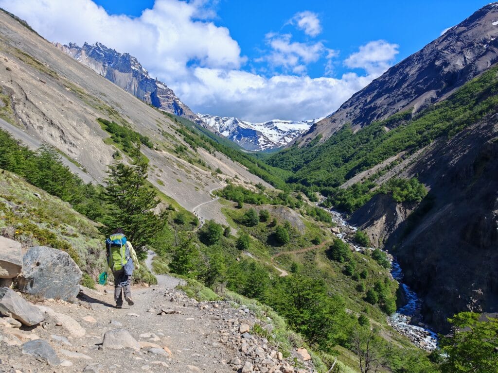 A hiker on a dusty path at Windy gap heading towards Chileno Camp near Mirador Base Torres