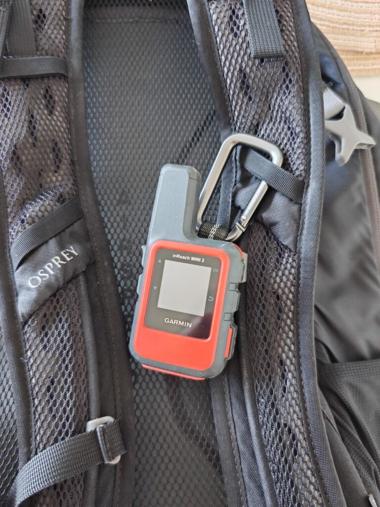 A red Garmin InReach Mini 2 clipped onto Osprey backpack