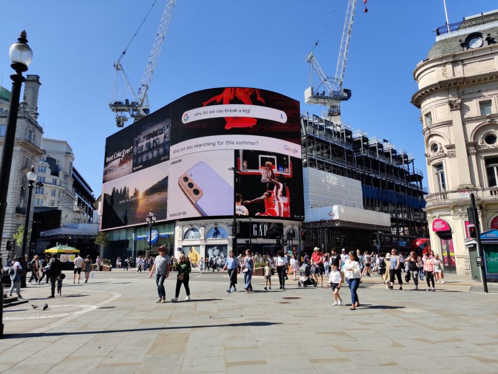 Picadilly Circus on a blue sky day with busy crowds in Central London