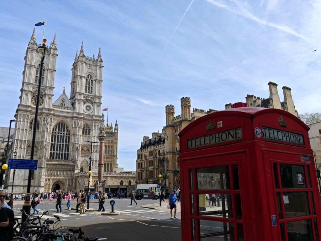 Westminster Abbey and a red telephone box on a blue sky day in London
