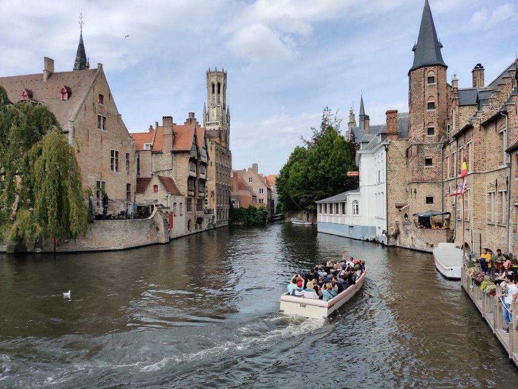 The Bruges Bell Tower and canal waterways with a boat on it and old buildings
