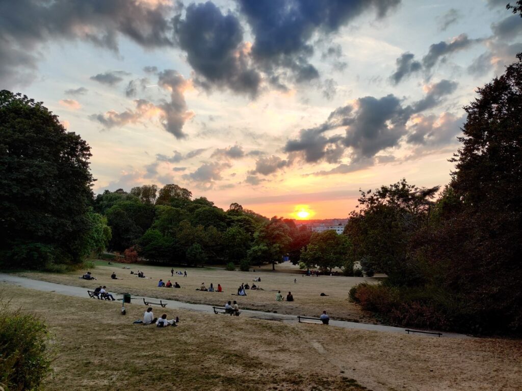 Parc de Forest at sunset in Brussels with a green space and crowds on the grass
